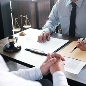 A man sits at a desk with a lawyer, discussing hiring a California personal injury attorney - Law Offices of David A. Kaufman, APC.